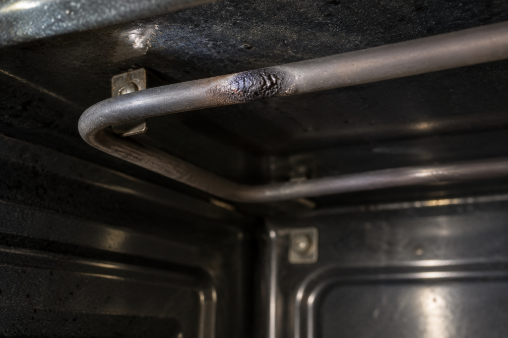 A close view of a cold oven broil element with one blackened blister on the rod.