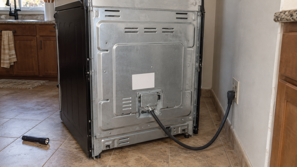 The back of a freestanding range pulled from the wall, showing a data label near the power cord.
